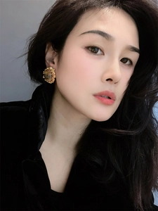 Close-up of vintage amber earrings with 18K gold relief detail worn by a model