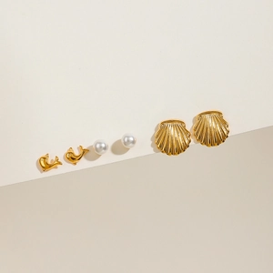 Détail du lot de trois boucles d'oreilles en acier avec dauphin doré, coquillage et perle