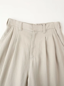 Detail of beige linen blend trousers with belt loops and elegant pleated front design