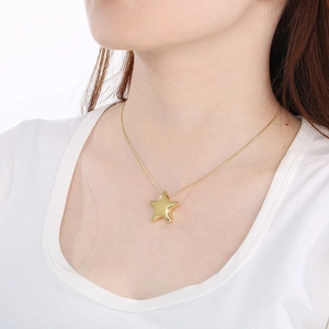 Polished gold stainless steel hollow star pendant necklace worn by a female model