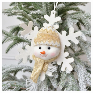 Close-up of plush snowman ornament with gold sequin hat hanging on a snowy Christmas tree