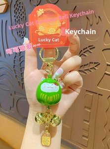Detail of green Maneki Neko Daruma bell keychain with gold Fuku character and charms