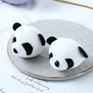 Close-up of cute panda plush charms on a decorative gold-rimmed plate with paper background