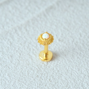 Macro shot of 16G gold opal ear stud with radiant sunburst design on textured surface