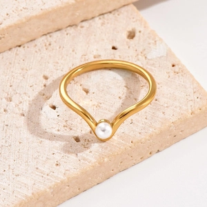Anello minimalista a V in acciaio al titanio con perla bianca su fondo travertino