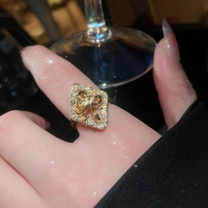 Close-up of gold clover flower ring with white zircon inlays and elegant bow detail
