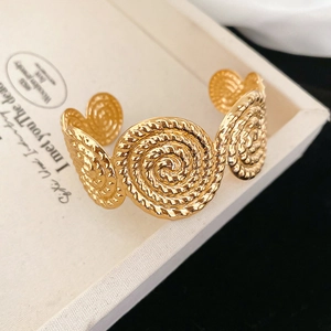Detailed macro view of vintage gold open bangle with spiral textured knot design