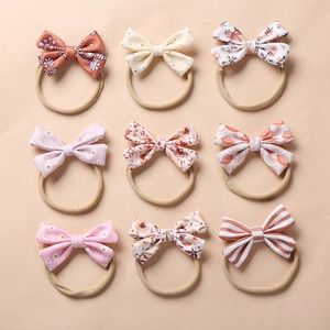 Set of 9 floral bow headbands for babies with soft nylon bands in a flat lay grid layout