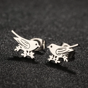 Minimalist silver bird stud earrings shown in a detailed close-up on a black texture