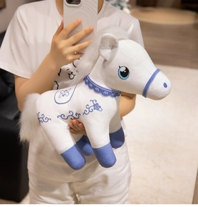 Detail of white plush pony with blue floral embroidery and soft plush fabric texture