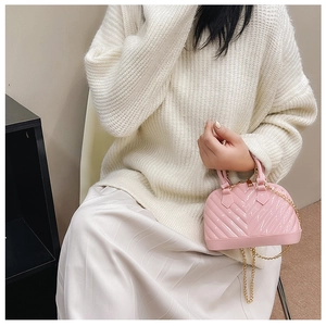 Pink jelly shell bag with V-shaped quilting and gold chain strap on a model