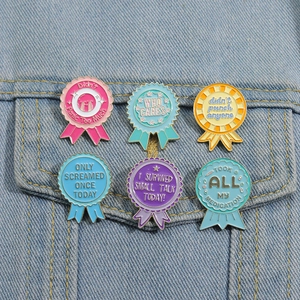Detail of six satirical enamel medal brooches pinned on a blue denim jacket pocket