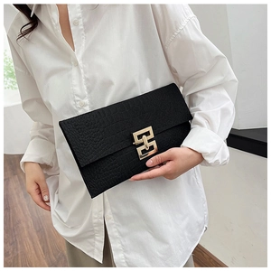 Detail of black crocodile texture envelope clutch bag with gold interlocking buckle