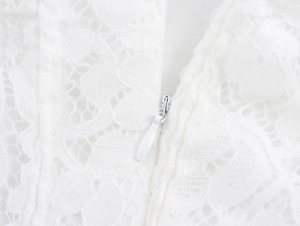 Close-up of invisible back zipper and delicate white lace texture on a mini dress