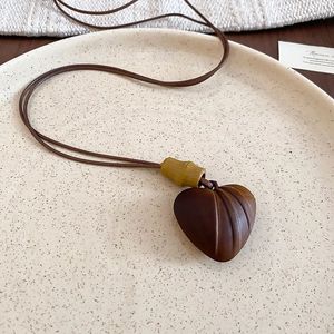 Detailed close-up of brown heart pendant with wood texture and bamboo-style accent