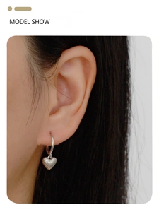 Close-up of model wearing silver S925 heart hoop earrings with ocean shell design