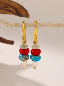 Macro detail of gold hoop earrings with turquoise, red beads, and white freshwater pearl