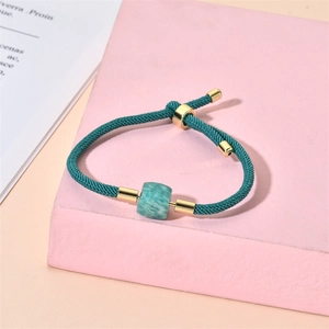 Détail d'un bracelet réglable en cordon tressé vert avec tube doré et pierre amazonite