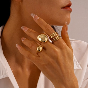 Détail d'une bague goutte d'or minimaliste et d'un ensemble de bagues étagées
