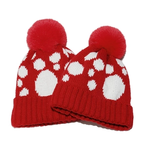 Rote Strickmütze mit weißem Pfotenmuster und Bommel für winterliche Outdoor-Aktivitäten