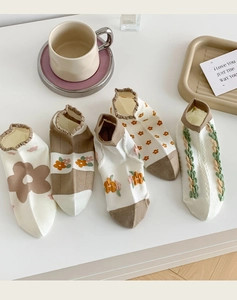 Flat lay of five pairs of cotton socks in earthy floral patterns with a coffee cup setup