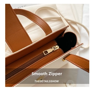 Macro shot of the smooth golden zipper and lychee pattern leather interior detail