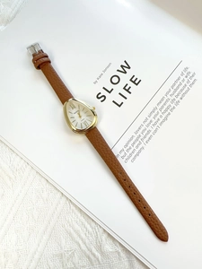 Macro detail of gold teardrop watch case with Roman dial and brown leather strap