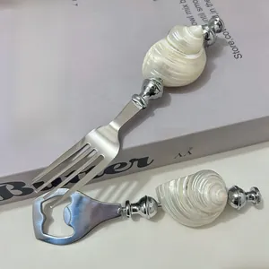 Close-up of stainless steel fork and bottle opener with natural white seashell handles