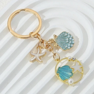 Detail of seashell and starfish enamel pendants with pearls on gold-toned keychain