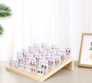 Detailed view of a multi-tier solid wood earring display stand with various jewelry pieces