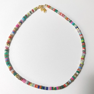 Detail of colorful beaded necklace with golden lobster clasp and butterfly charm pendant