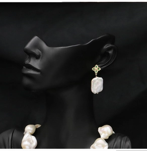 Detail of baroque pearl earrings with green gemstone flower and matching necklace