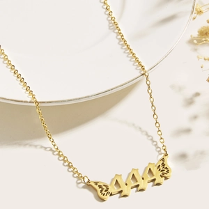 Detailed close-up of gold 444 angel number pendant with butterfly wings on fine chain