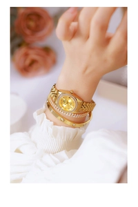 Close-up of gold women watch with crystal bezel and matching metal bracelets