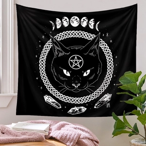 Detailed view of black and white mystic cat tapestry with moon phases and stars on a white wall