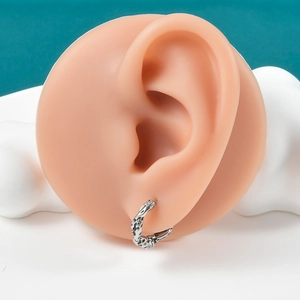 Macro detail of silver punk ear cuff with black leopard texture on silicone model