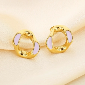 Macro detail of gold-plated earrings with light purple enamel on champagne silk fabric