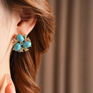 Vue détaillée des boucles d'oreilles fleur or vintage avec turquoise et zircons