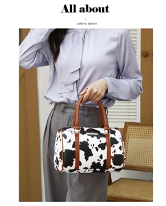 Cow print Boston bag with brown handles styled on a model in a natural indoor setting