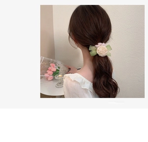 Detailed view of large beige rose and green leaves on a soft mesh scrunchie for low ponytail