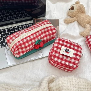 Detail of red cherry charm on knitted checkered pencil case with soft plush texture