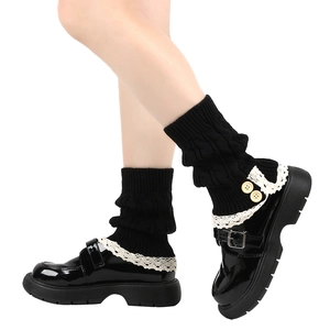 Close-up of black knitted leg warmers with white lace trim and beige buttons details