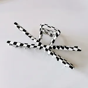 Detailed view of a large black and white checkerboard hair claw clip with silver spring