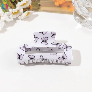 Detail of white acrylic square hair claw clip with elegant purple butterfly patterns