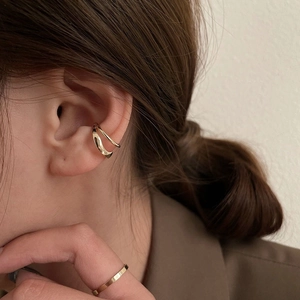 Dettaglio dell'ear cuff dorato a doppio strato e dell'anello sottile sulla modella