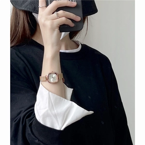 Minimalist square dial watch with golden band, elegantly worn on a woman's wrist