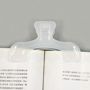 Macro shot of a transparent curved plastic book clip holding open pages on a flat book
