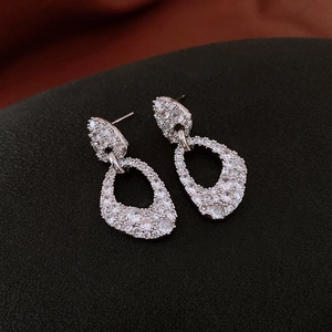 Détail de boucles d'oreilles argentées avec design ajouré et micro-pavage de zircons blancs