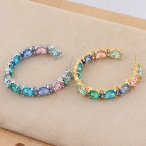 Detailed view of C-shaped earrings with colorful oval-cut cubic zirconia in gold and silver