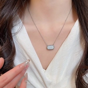 Detail view of silver resin rectangle pendant on a model wearing white clothing
